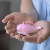 Pink whale keychain resting in both hands, highlighting the keychain's size and intricate details.